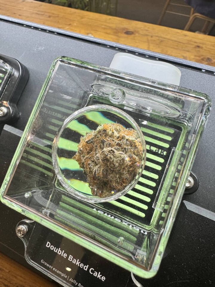 Close-up of a cannabis bud under a magnifying lens, labelled Double Baked Cake.